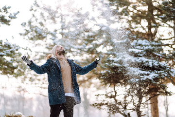 Young stylish man in a snowy forest. Handsome man enjoying sunny winter weather. Concept of people, vacation.