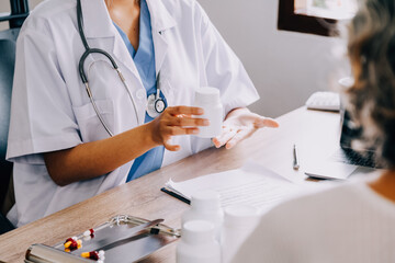 Female pharmacist selling medications at drugstore to a senior woman customer while using tablet