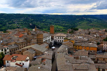 Photo of a view of the historic part of the city with stone houses, numerous churches and the Torre Dodecagonale tower against a stormy sky in the city of Orvieto, Umbria region, Italy - obrazy, fototapety, plakaty