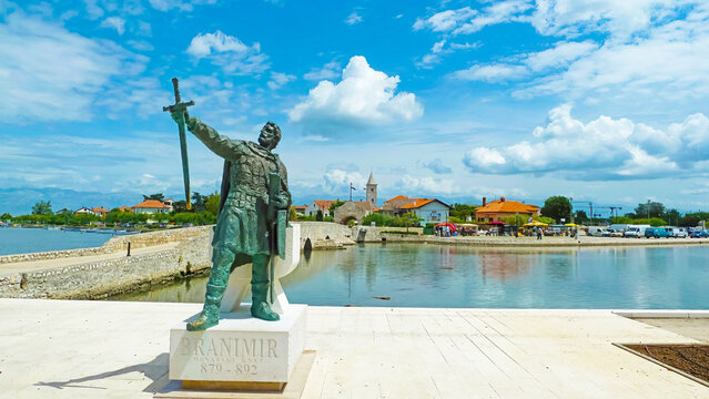 Island Nin, Croatia - May 9. 2014: View on harbor of adriatic village with sculpure of duke branimir against blue sky with clouds (focus on monument)