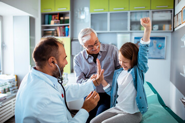 Doctor sharing a cheerful moment with a young girl and her grandfather