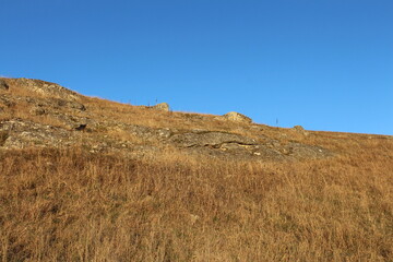 A grassy hill with a hill in the background
