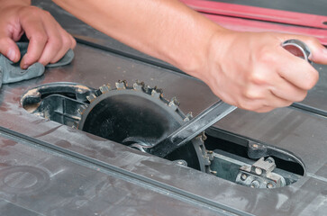 Installing circular saw on circular saw in carpentry workshop. The hands of the carpenter install the round saw