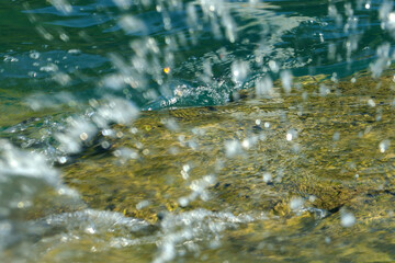 Sea wave splash on rocky shore, closeup shot, selective focus, blurred