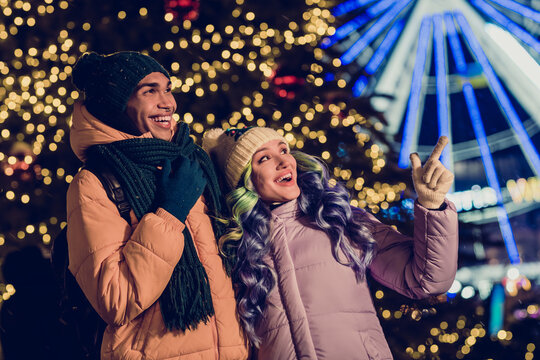 Photo of funny impressed excited optimistic beautiful couple guy girl look indicating empty space fir tree ferris wheel on background