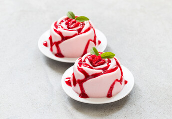 Vegan Raspberry Cream dessert, Panna Cotta in the shape of a rose, with raspberry sauce, on a plate. Close up