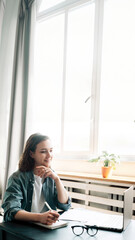 Young woman multitasking with laptop computer at office and student girl working remotely from home. Online work, study, freelance, and modern office lifestyle concept.