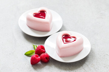 Vegan dessert. Raspberry cream cake in the shape of a heart with raspberry sauce in the center. On a plate. Light gray background. Close-up. Valentine's Day