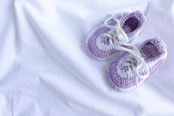 Knitted booties-socks on a purple knitted plaid for newborns.