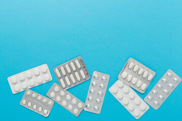 Pills in blister packaging on color background, top view