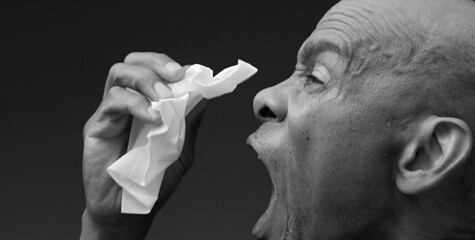 man catching the cold and flu man blowing nose after catching a cold with grey background with...