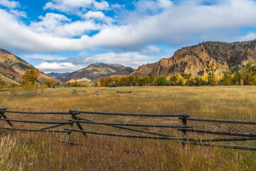 Fototapeta na wymiar Landscape of Pasture Land in an Absaroka Mountain Valley with Early Morning Light in Fall Color on a Cloudy Autum Day on the Road from Cody, Wyoming, USA to Yellowstone National Park