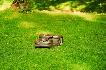 Robotic lawn mower on grass, side view. Close up isolated of automatic lawn mower. Smart lawn...