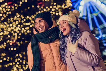 Photo of positive excited american guy lady wear windbreakers watching xmas miracle together outside urban ferris wheel market park