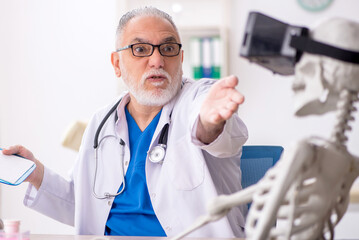 Old male doctor examining skeleton in the clinic