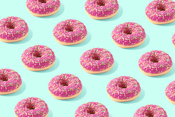 Trendy food pattern made with pink doughnut on bright light blue background. Minima food concept.
