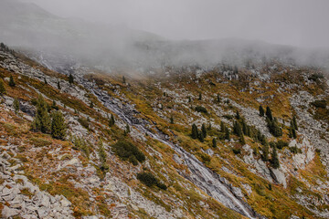 
The mountains, shrouded in a delicate veil of clouds, create an ethereal and mysterious landscape.