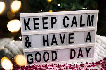 Lightbox with the words Keep calm and have a nice day. The photo is decorated with New Year's golden bokeh.