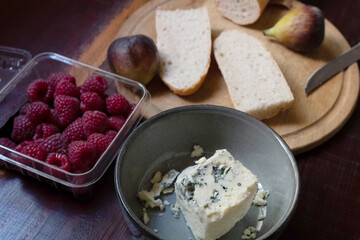 Baguette with blue cheese, figs and raspberries on wooden cutting board