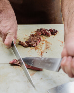 Churrasqueiro cortando carne de boi em tábua de corte