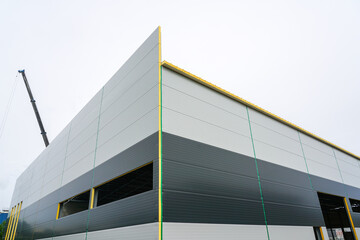 A new modern facade of an unfinished industrial facility made of gray sandwich panels - obrazy, fototapety, plakaty