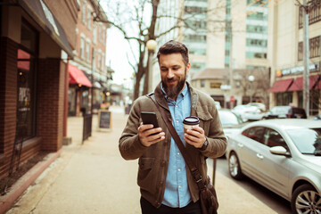 Man enjoying his coffee while browsing his phone on a city street