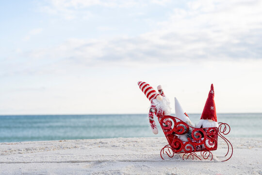 Christmas Gnome on beach in a red sled on a sunny winter day  