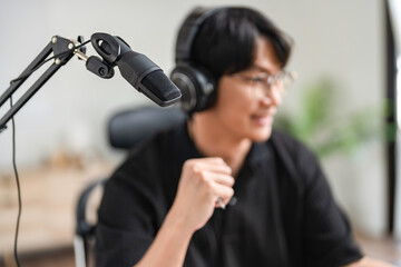 Man host in headphone using laptop with microphone to talking and recording audio podcast in studio
