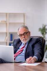 Old male employee working in the office