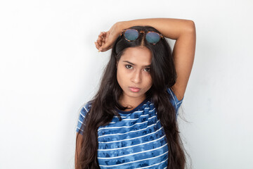 Naklejka premium Studio shot of a young, beautiful Indian female model in casual wear, wearing blue and white printed top and a clear eyeglass against white background. Advertisement shoot. Eyeware product shoot.