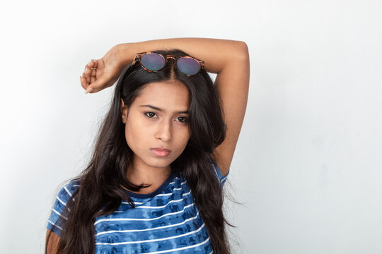 Studio shot of a young, beautiful Indian female model in casual wear, wearing blue and white printed top and a clear eyeglass against white background. Advertisement shoot. Eyeware product shoot.