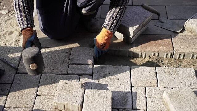worker at a construction site lays paving slabs