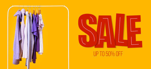 Rack with clothes and word SALE on yellow background