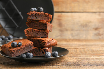 Plate with pieces of tasty chocolate brownie on wooden background
