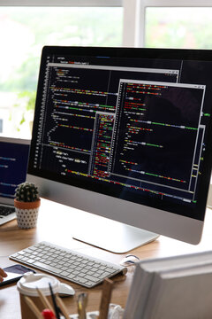 Computer monitor with programming code at programmer's workplace in office