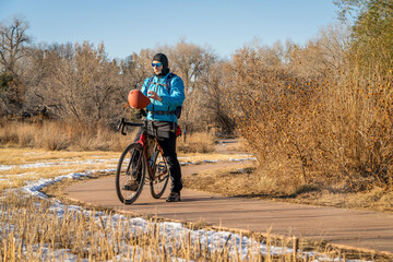 senior male cyclist with a touring gravel bike on a biking trail in Fort Collins, Colorado in cold...