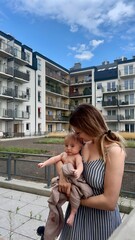 A young woman with a baby in her arms rests on the terrace