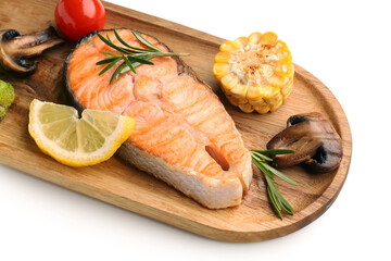 Wooden board with tasty grilled salmon steak, lemon and vegetables on white background