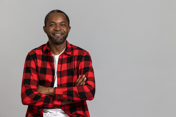 Confident happy black bearded man wearing red checkered shirt crossed hand looking at camera