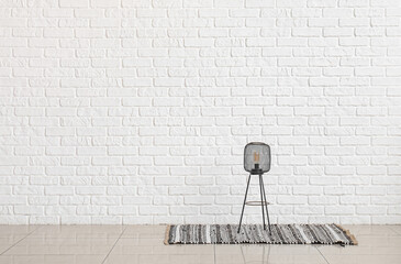 Small lamp on rug near white brick wall