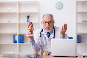 Old male doctor cardiologist working in the clinic