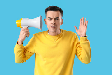 Young man with hearing problem and megaphone on blue background
