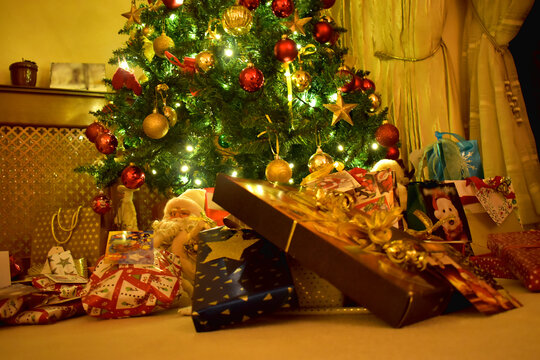 Close-up of colorful Presents and gift boxes under a Christmas tree with bright light in the cozy living room, decoration on Christmas holiday in the UK.
