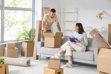 Happy young couple packing things in room on moving day