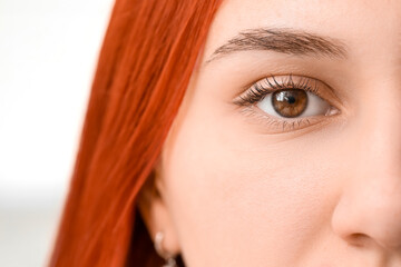Young woman with hazel eyes on grey background, closeup