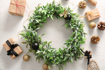 Christmas mistletoe wreath with balls, cones and gift boxes on white background