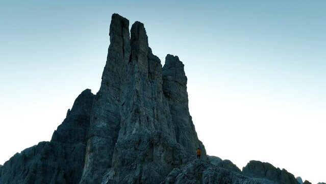 Uomo ai piedi di una vetta delle dolomiti, ripresa aerea in 4k