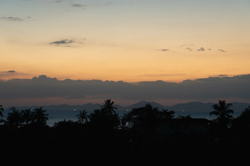 Twilight in Thailand - close up view on palms, sea and mountains at horizon line. Ao Nang, Thailand