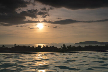 Dramatic tropical evening Sun in Thailand - view over roof top swimming pool in luxury hotel. Dark...