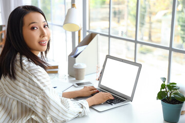 Young Asian woman working with laptop at home office